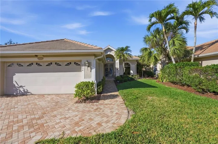 View of front of house with a front lawn, a garage, decorative driveway, a tile roof, and stucco siding