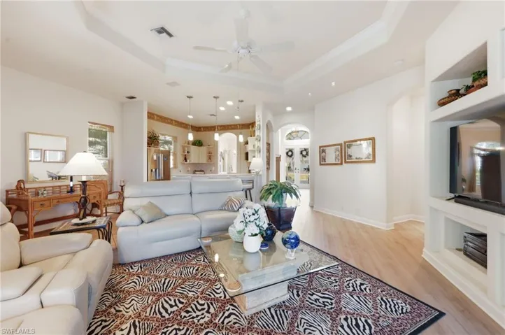 Living room featuring a ceiling fan, light wood-style flooring, arched walkways, and ornamental molding