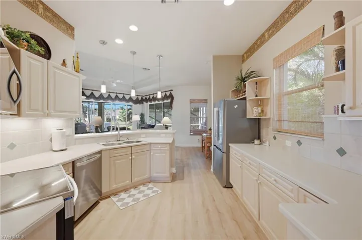 Kitchen featuring tasteful backsplash, stainless steel appliances, a peninsula, and light countertops