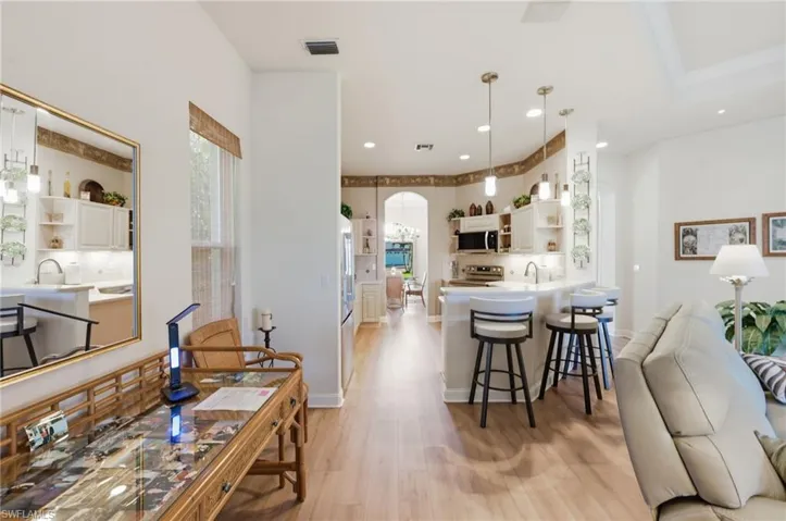 Kitchen with open shelves, arched walkways, a peninsula, decorative light fixtures, and a kitchen bar