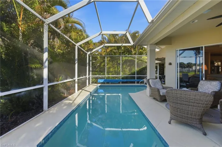 Outdoor pool with glass enclosure, a patio area, and a sunroom