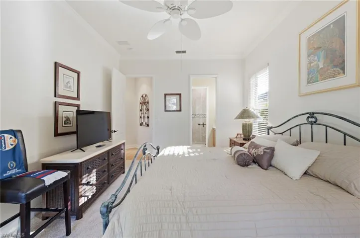 Carpeted bedroom featuring ornamental molding, ceiling fan, and ensuite bath
