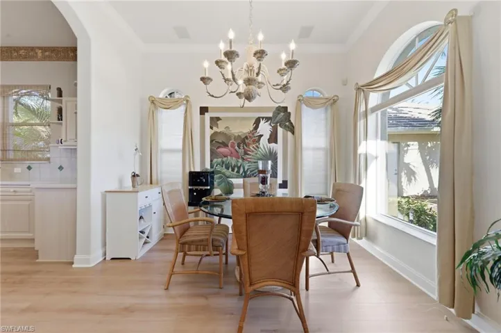 Dining room featuring light wood-style flooring, ornamental molding, a chandelier, and arched walkways