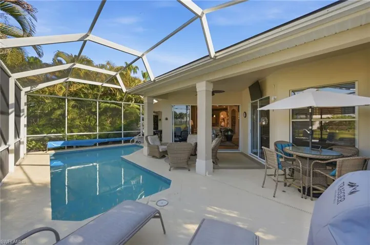 Outdoor pool with a sunroom, glass enclosure, a patio, and outdoor dining space