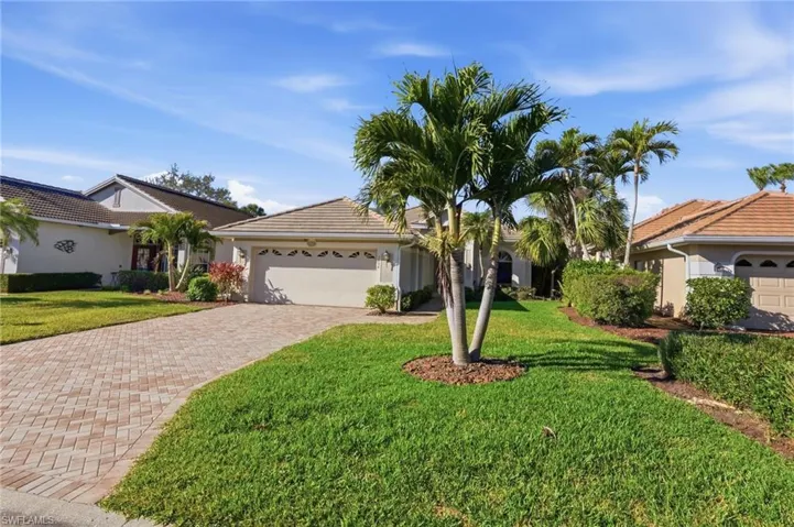 Ranch-style home featuring an attached garage, decorative driveway, a front lawn, stucco siding, and a tile roof