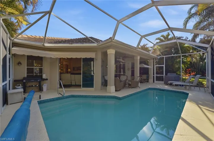View of pool with a sunroom, a covered pool, glass enclosure, and patio surround