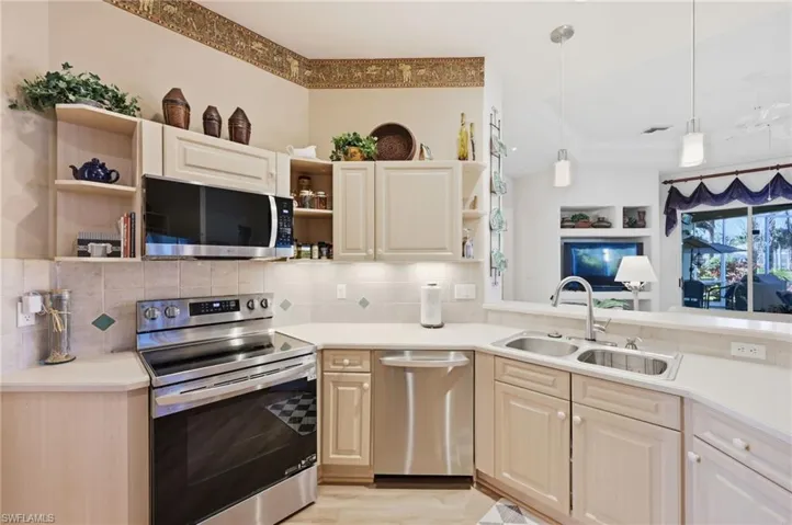 Kitchen featuring stainless steel appliances, open shelves, pendant lighting, backsplash, and light wood-type flooring