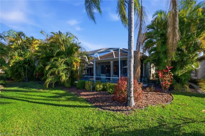 Back of property featuring a sunroom, glass enclosure, and a yard
