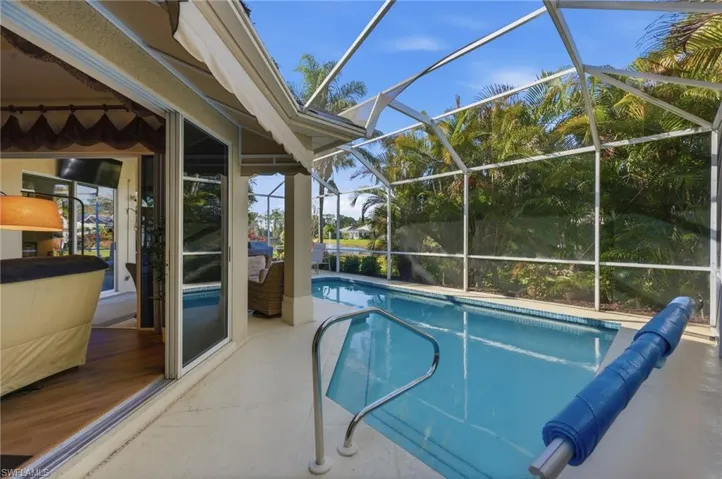View of swimming pool featuring a covered pool, patio surround, a sunroom, and a lanai