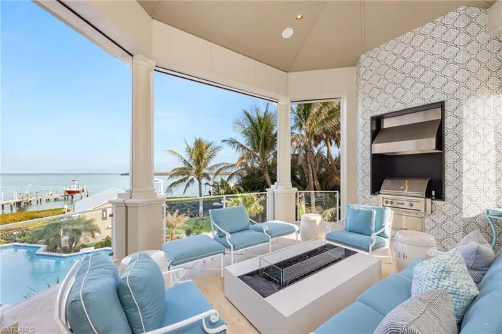 Covered back patio with built in grill, custom tile, fire table, remote controlled screens and Bay views