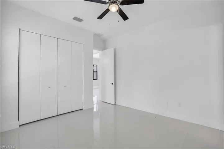 Unfurnished bedroom featuring a closet, light tile flooring, and ceiling fan