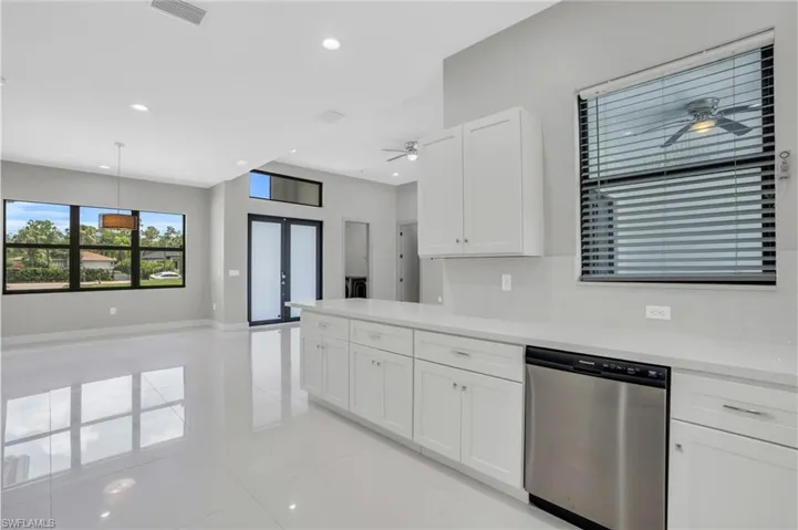 Kitchen featuring ceiling fan, dishwasher, decorative light fixtures, light tile floors, and white cabinetry