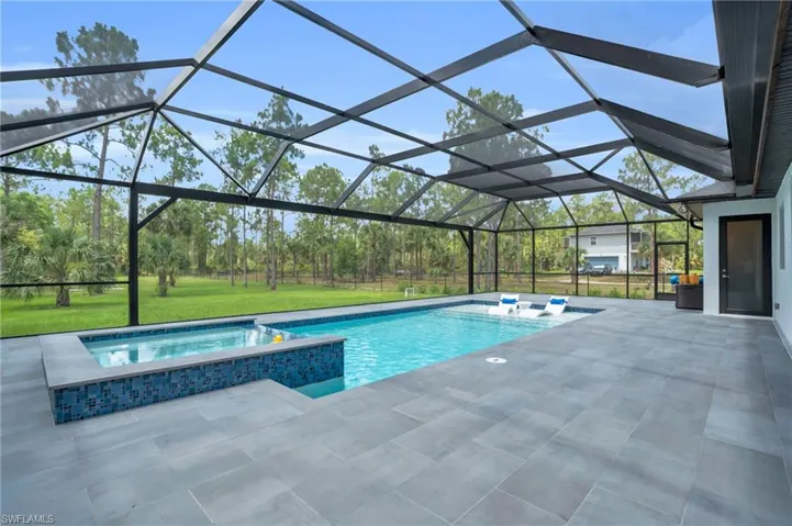 View of pool with a lawn, super screen lanai, an in ground hot tub, and a patio
