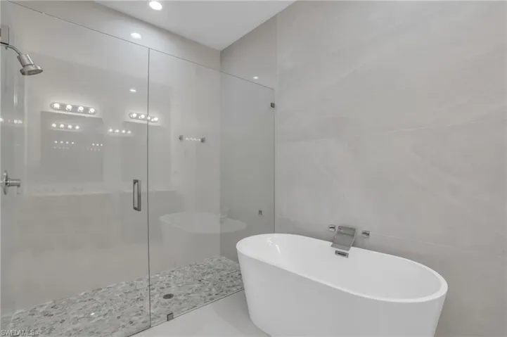 Bathroom with tile walls, tile floors, and independent shower and bath