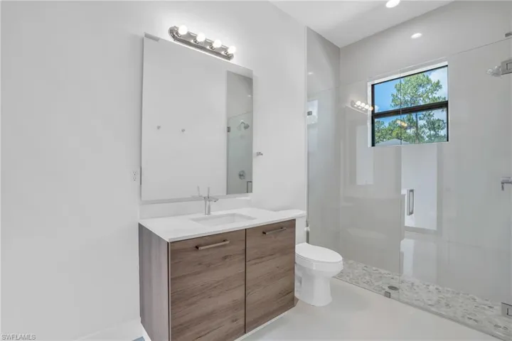 Bathroom featuring a shower with shower door, tile flooring, toilet, and large vanity