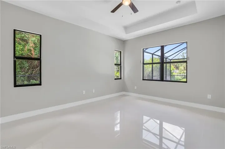 Tiled spare room with ceiling fan and a raised ceiling