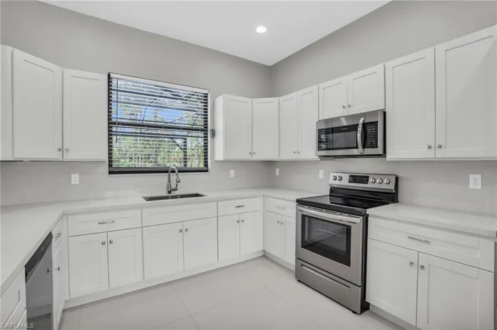 Kitchen with appliances with stainless steel finishes, white cabinetry, and sink