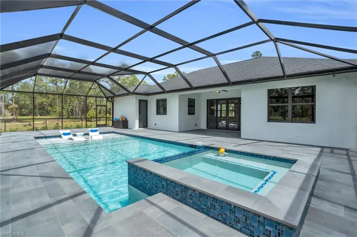 View of swimming pool with ceiling fan, a patio area, a lanai, and an in ground hot tub
