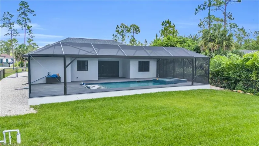 Rear view of house with a lawn, a lanai, and a patio area