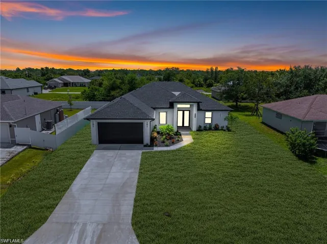 View of front of home with a shingled roof, driveway, a garage, and stucco siding
