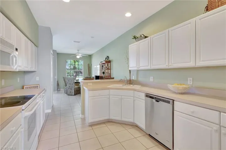 Kitchen featuring white appliances, a kitchen breakfast bar, white cabinetry, a peninsula, and recessed lighting and a desk area