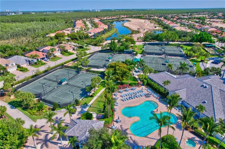 Aerial view of property and surrounding area featuring a large body of water, a pool area, and nearby suburban area