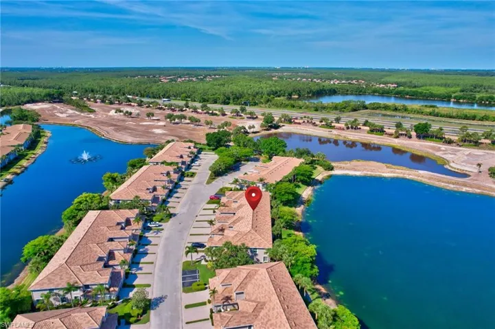 Aerial view of a the home, the surrounding water and of the golf course under renovation and the wooded area in the community