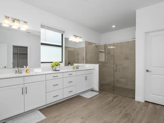 Owner bath features an oversized vanity with dual sinks, a huge walk-in shower with frameless glass enclosure, and a window with privacy film allowing plenty of natural light.