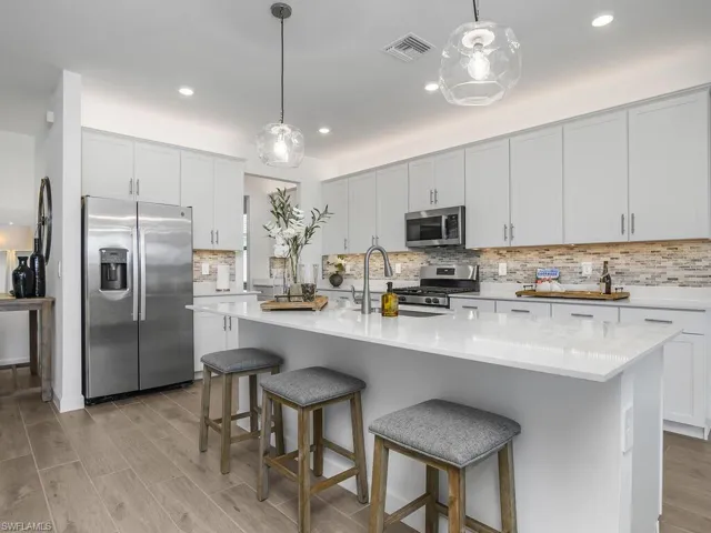 Upgraded kitchen featuring custom glass tile backsplash, pendant lighting, custom shelving in walk-in pantry, Over cabinet and under cabinet lighting, and additional recessed lights making this home bright and airy.
