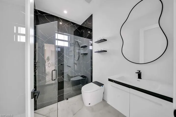 Full bath with vanity, a marble finish shower, and light marble finish floors