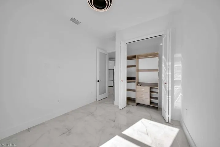 Unfurnished bedroom with light marble finish flooring and a closet