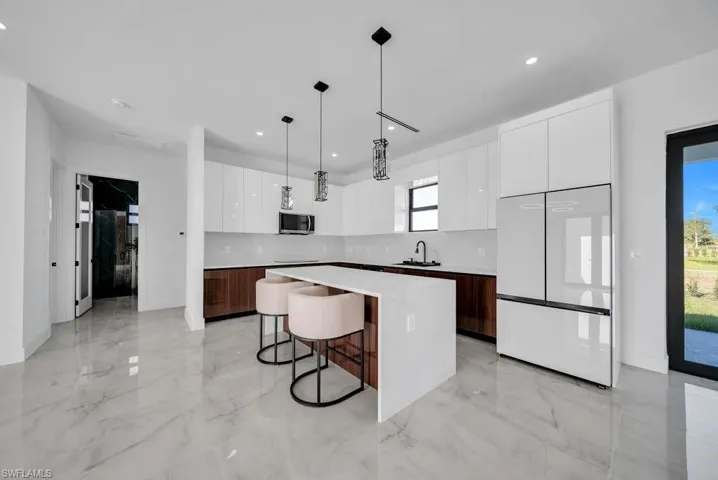 Kitchen featuring white cabinetry, modern cabinets, freestanding refrigerator, and recessed lighting