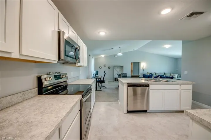 Kitchen featuring white cabinetry, stainless steel appliances, neutral countertops, and recessed lighting