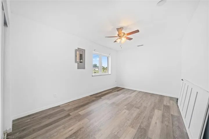 Spare room with electric panel, wood finished floors, and a ceiling fan