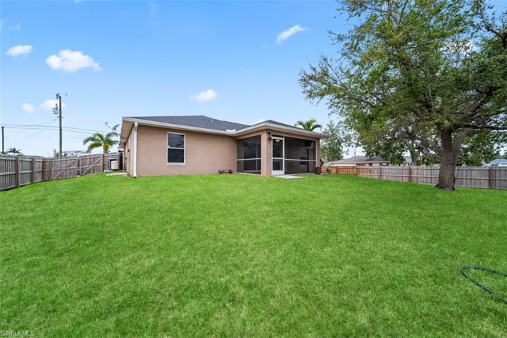 Rear view of house featuring a fenced backyard, a sunroom, and stucco siding
