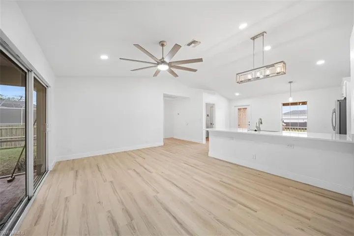 Unfurnished living room with lofted ceiling, a ceiling fan, light wood-type flooring, and recessed lighting