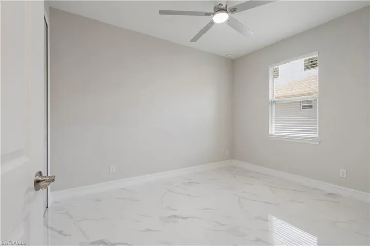 Empty room featuring a ceiling fan, marble finish floor, and baseboards