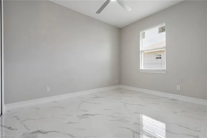 Unfurnished room with a ceiling fan, marble finish floor, and baseboards