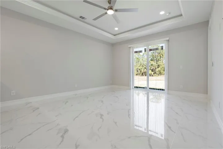 Unfurnished room with marble finish floor, visible vents, a tray ceiling, and recessed lighting