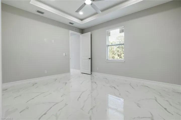Spare room featuring visible vents, a raised ceiling, ceiling fan, marble finish floor, and recessed lighting