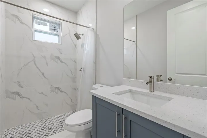 Full bathroom featuring vanity, a marble finish shower, and toilet