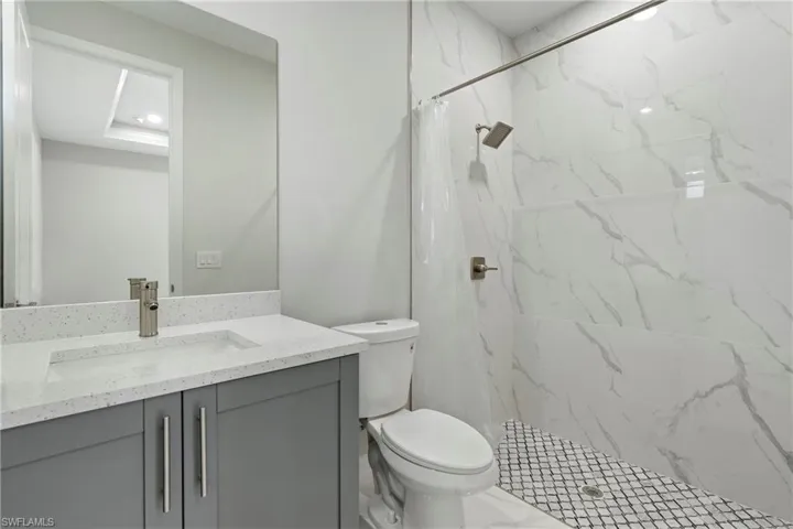 Full bath featuring toilet, marble finish floor, a shower stall, and vanity