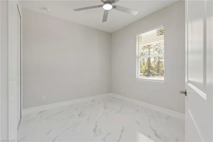 Spare room featuring marble finish floor, baseboards, and a ceiling fan