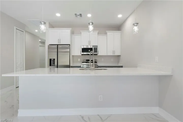 Kitchen with visible vents, appliances with stainless steel finishes, marble finish floor, white cabinetry, and a sink