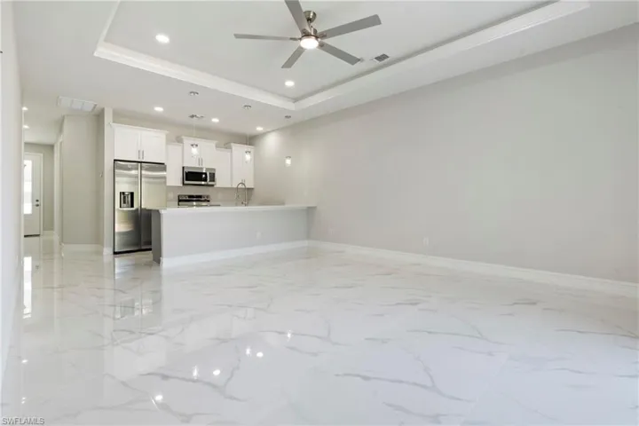 Unfurnished living room with marble finish floor, recessed lighting, a raised ceiling, visible vents, and a sink