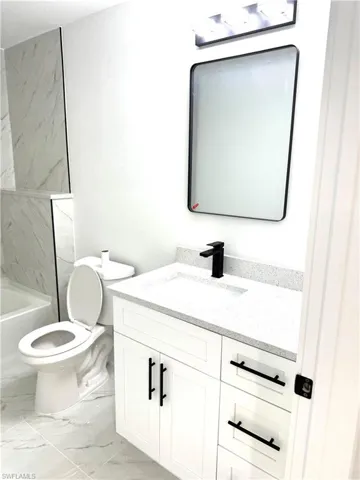 Full bathroom featuring tiled shower / bath, vanity, and toilet
