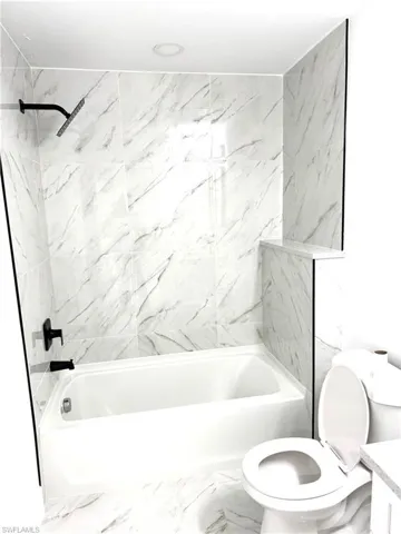 Full bathroom with tiled shower / bath, vanity, and toilet