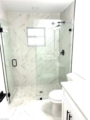 Bathroom featuring walk in shower, vanity, and toilet