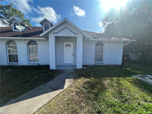 View of front of house featuring stucco siding, a front yard, and roof with shingles