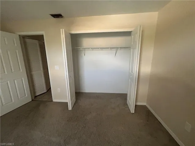 Unfurnished bedroom featuring dark carpet and a closet